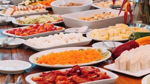 Mesa de buffet con diferentes alimentos y una planta decorativa.