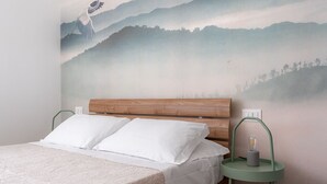A bedroom with a wooden headboard, white bedding, and a wall mural of a bird in flight. - Santamaria Apartment by Wonderful Italy (Siracusa)