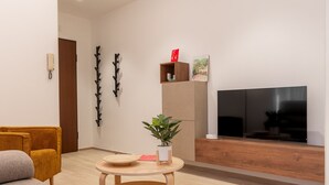A modern living room with a sofa, a coffee table, a TV, and a plant. - Santamaria Apartment by Wonderful Italy (Siracusa)