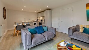 Un appartement moderne comprenant un coin repas, une cuisine et deux canapés.