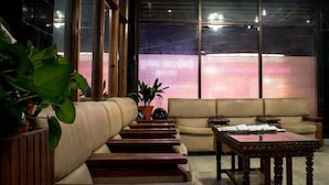 A modern living room with a sofa, wooden coffee table, and potted plants. - Hotel Kamal (Kathmandu)