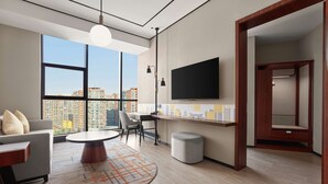 Un salon moderne doté d’une grande fenêtre, d’un téléviseur à écran plat, d’une table basse ronde et d’un canapé.