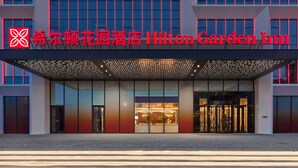 L’extérieur de l’hôtel Hilton Garden Inn se distingue par sa façade moderne, ses grandes fenêtres et son entrée imposante.