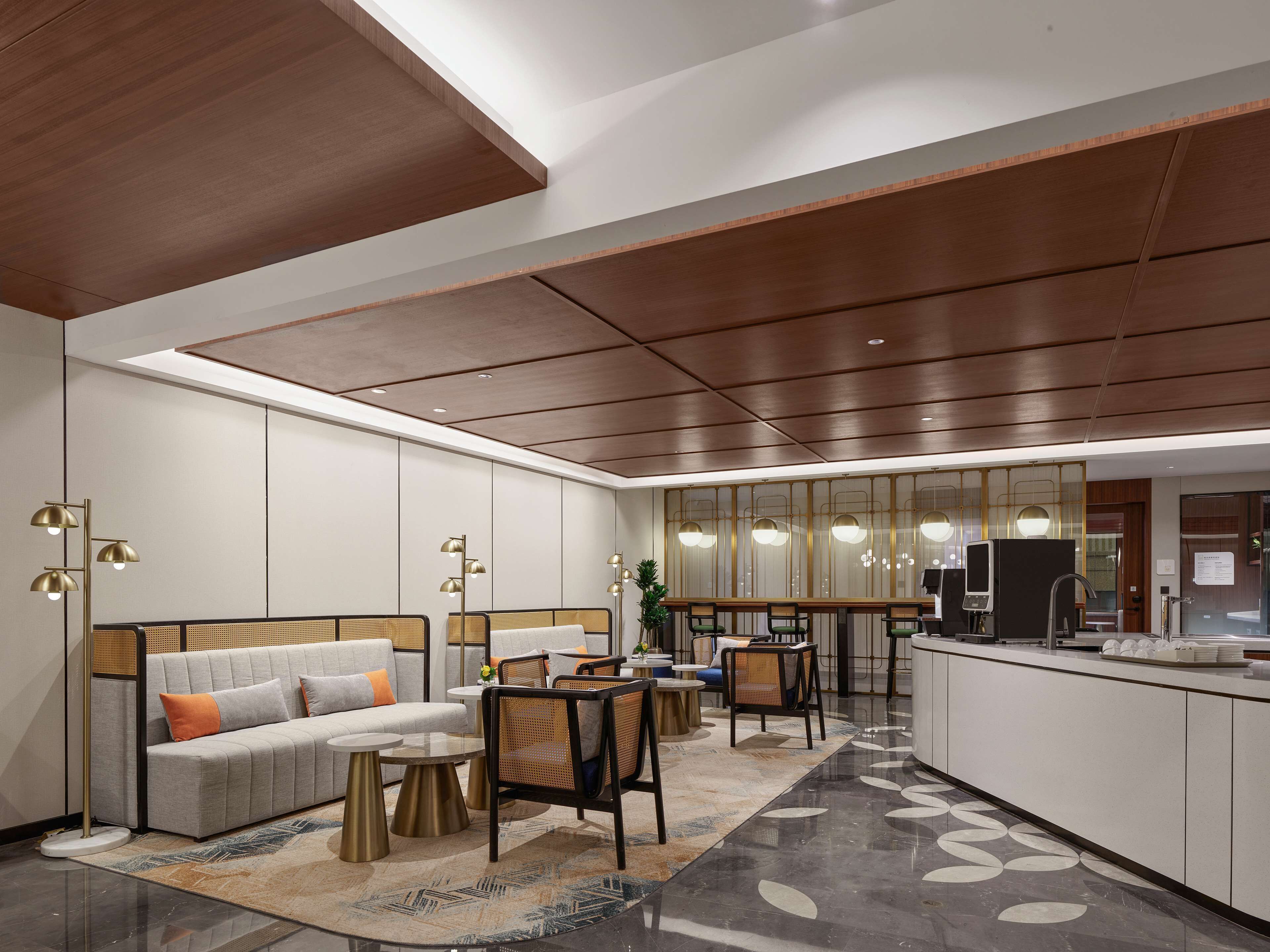 A modern hotel lobby with a sofa, chairs, a small table, and a reception desk.