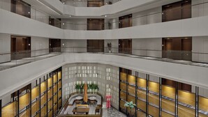 Un atrium à plusieurs niveaux doté d’un espace de repos central, de rampes en verre et d’un plafond agrémenté d’une verrière.