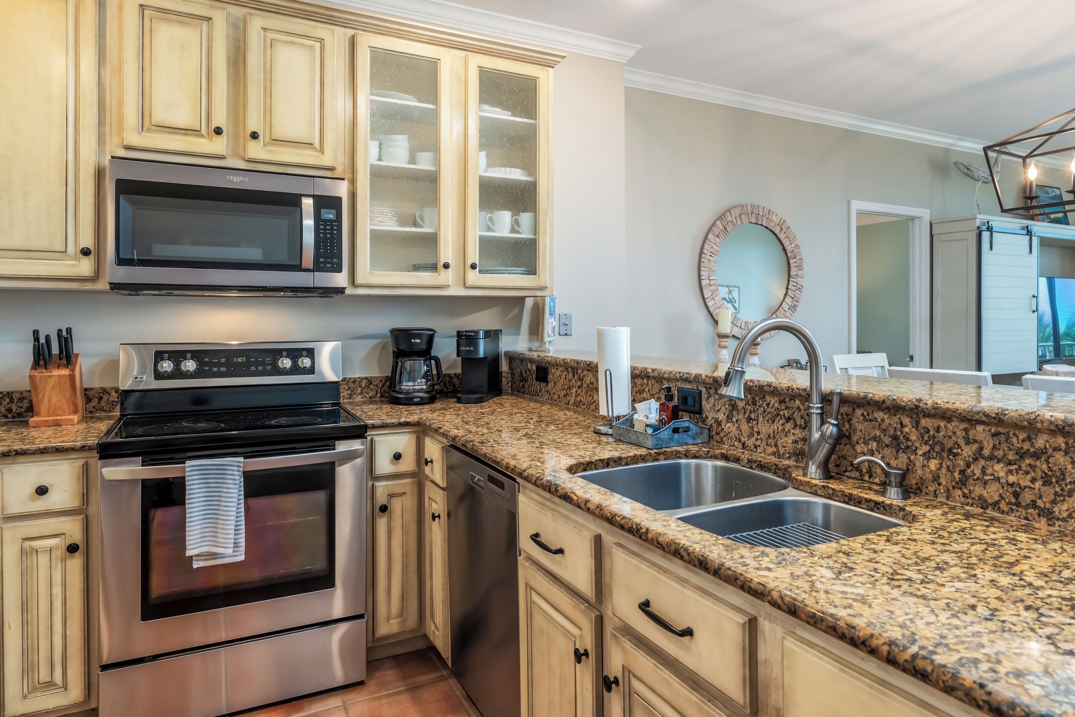 A kitchen with stainless steel appliances, granite countertops, and light wood cabinetry.