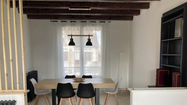 A dining area with a wooden table, black chairs, and pendant lights.