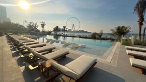 Un espace aménagé au bord de la piscine, avec des chaises longues et une vue sur une grande roue.