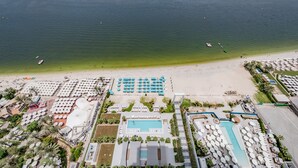 Vue aérienne d’un complexe hôtelier doté d’une grande piscine, d’une plage et de nombreux transats.