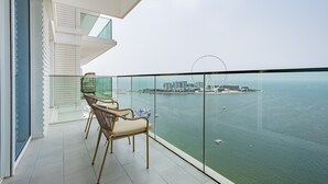 Un balcon avec vue sur la mer et une grande roue visible au loin.
