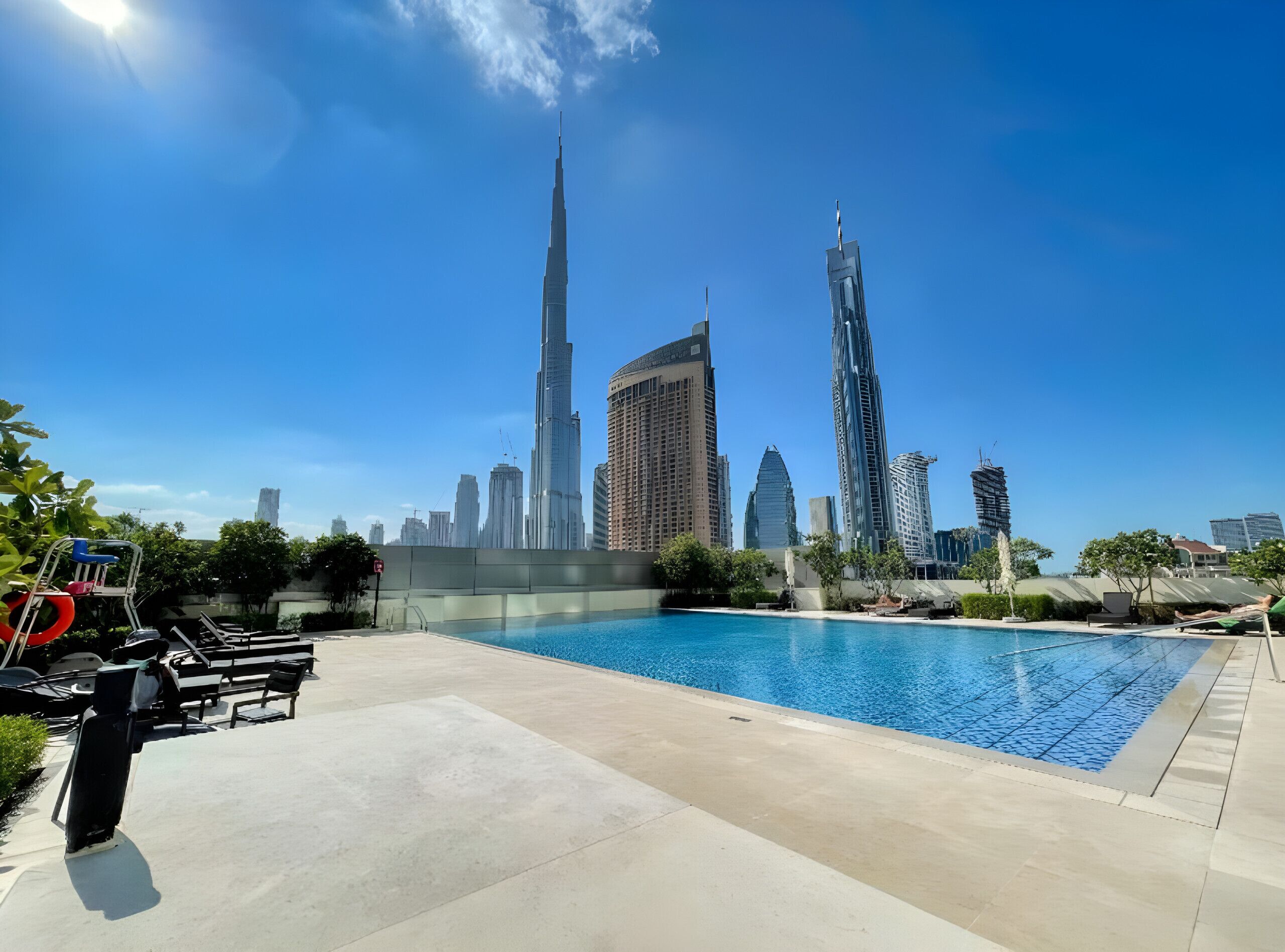 A swimming pool with a city skyline in the background, including the Burj Khalifa.
