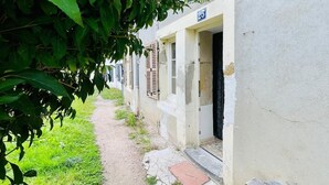Kapea polku johtaa riviin valkoisia rakennuksia, joiden yläpuolella on numeroitu kyltti, jossa lukee ’25’.