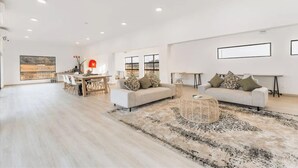 A spacious living area with a dining table, sofas, and a large rug.