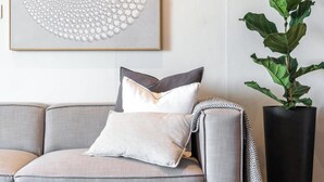 A modern living room with a grey sofa, a round coffee table, and a large abstract painting on the wall.