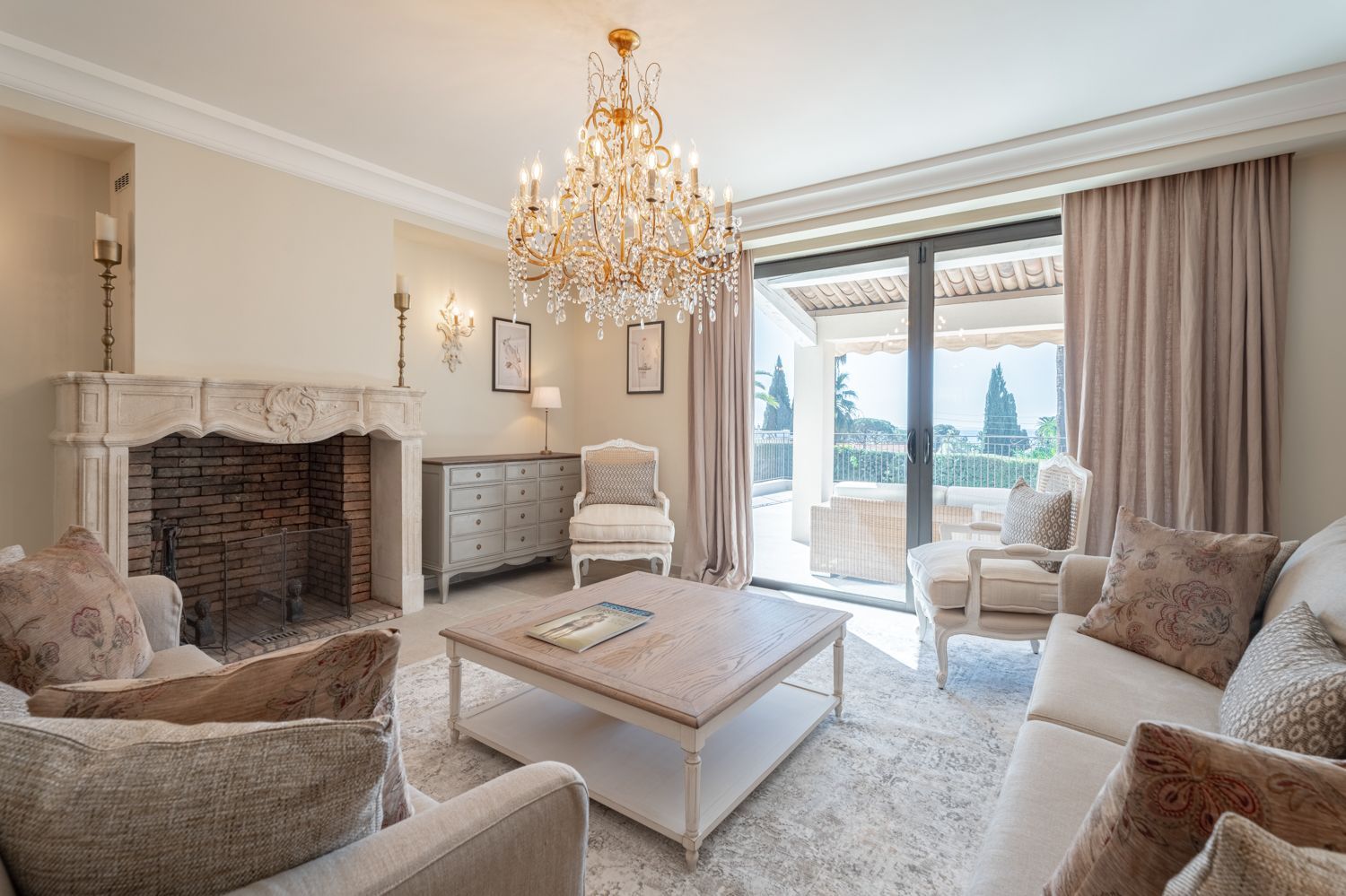 A spacious living room with a fireplace, a chandelier, and a view of the city.