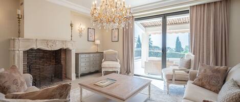 A spacious living room with a fireplace, a chandelier, and a view of the city.
