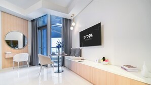 A modern, well-lit room with a wooden reception desk, a round mirror, two white chairs, a small table with a vase, and a framed picture. - Luxury Skyline Studio | Pool and Stunning Views (Dubai)