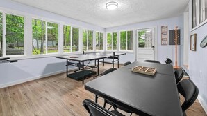 Una habitación amplia con ventanas grandes, una mesa con sillas y un banco para levantamiento de pesas.