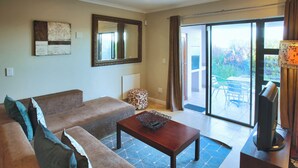 Una sala de estar con sofá, mesa de centro, televisor y puerta corrediza de vidrio que da a un área exterior.