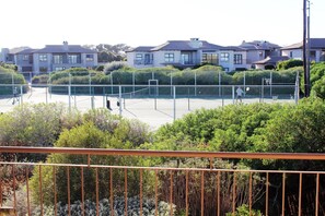 A tennis court surrounded by residential buildings and greenery.