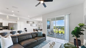 A modern living room with a leather sofa, a coffee table, and a balcony with a view of the outdoors.