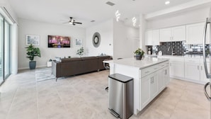 A modern kitchen with white cabinetry, a central island, and a built-in oven.