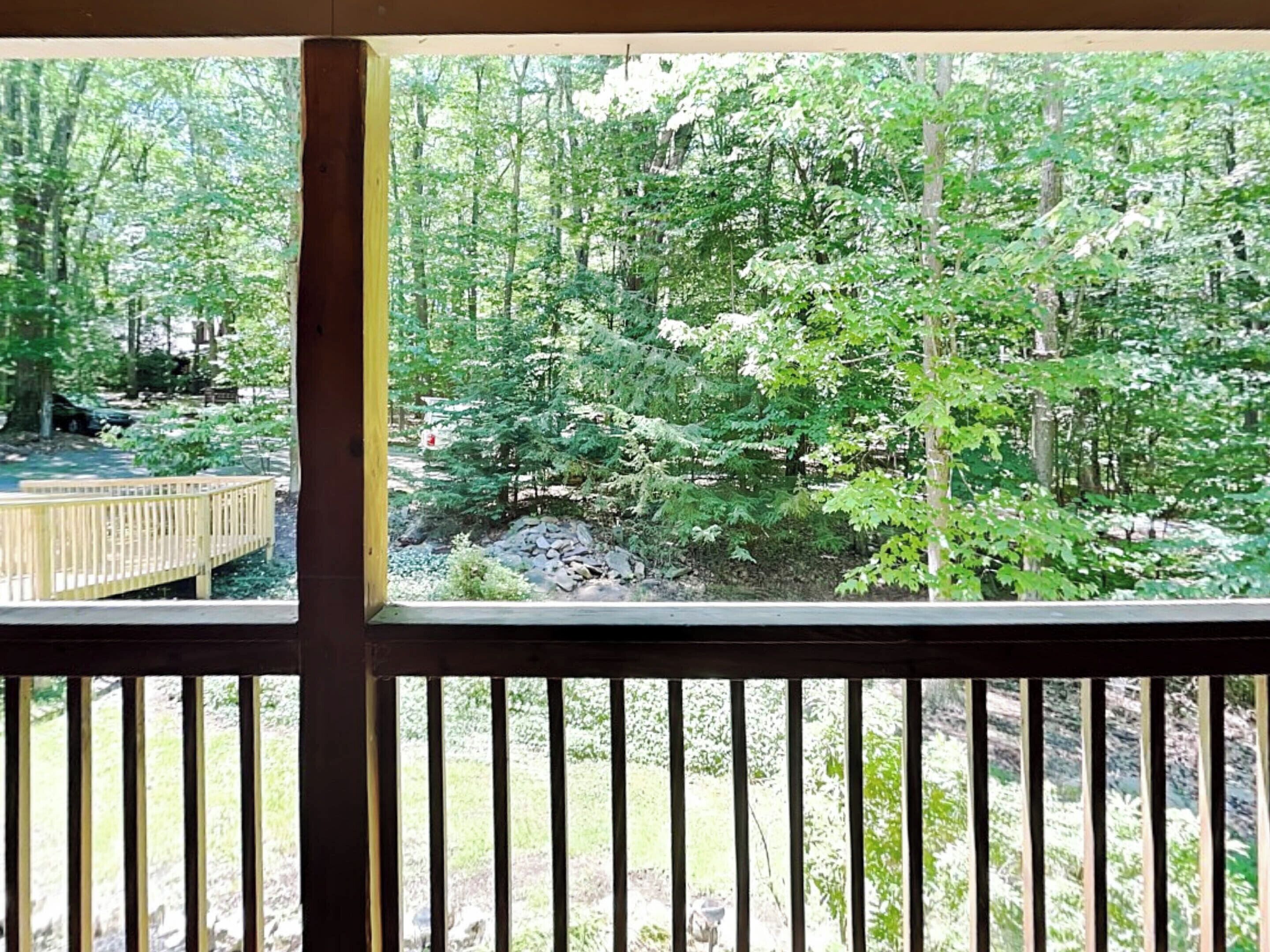 A wooden deck with a view of a forested area.