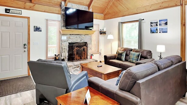 Ein gemütliches Wohnzimmer mit Kamin aus Stein, Ledersofa und Wandfernseher.