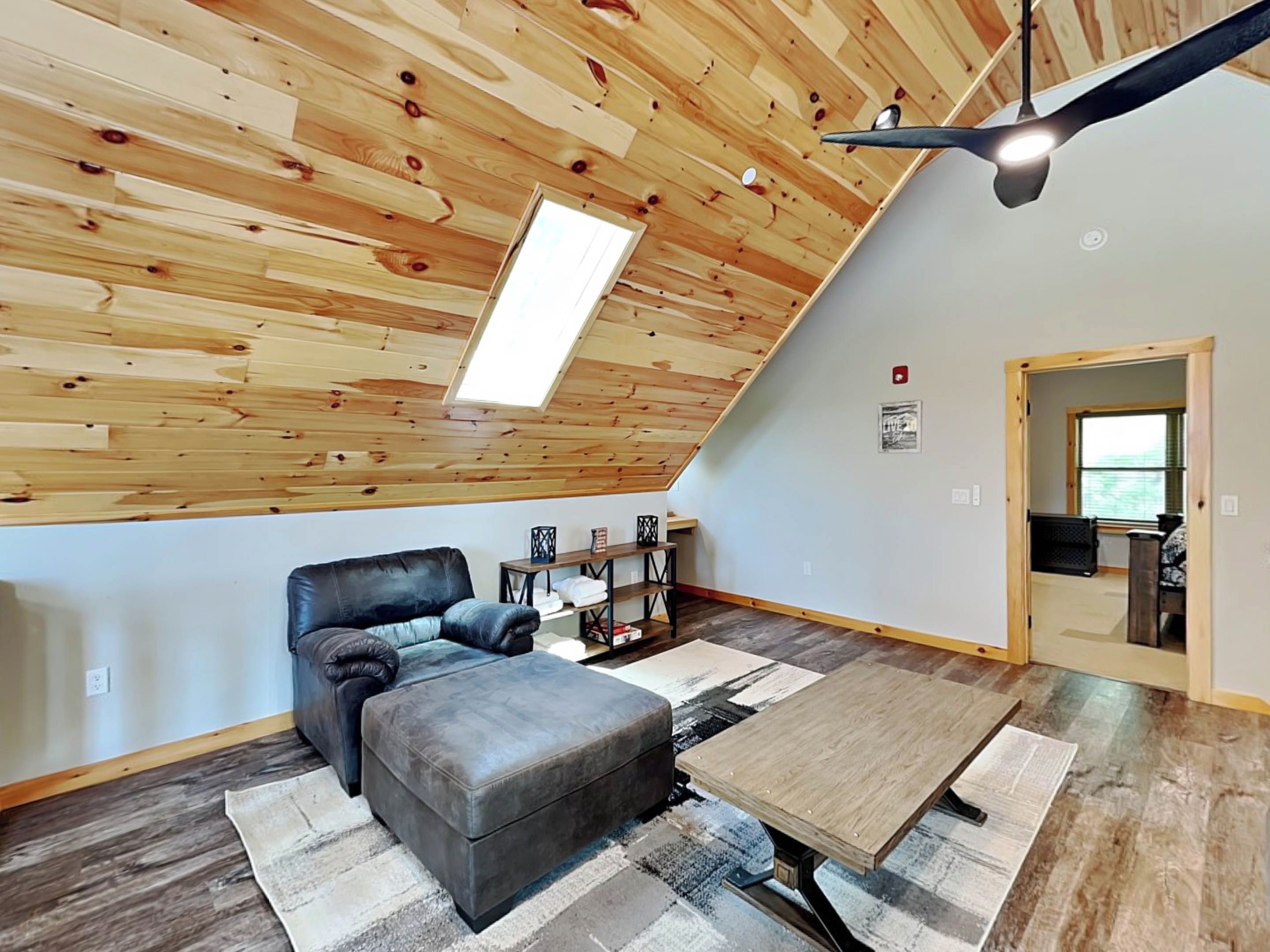 A loft-style room with a sloped ceiling, a sofa, a coffee table, and a skylight.