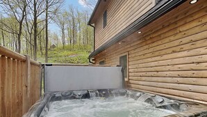 A hot tub with a wooden exterior, surrounded by a wooden fence and a house in the background. - Sunset Bluff by Taylor Made Deep Creek (McHenry)