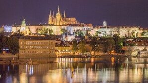 Une vue nocturne d’une ville historique, avec une cathédrale imposante et une rivière qui reflète ses lumières.