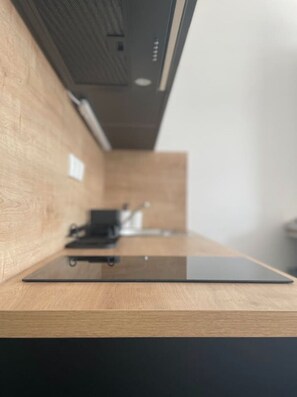A modern kitchen with a wooden countertop and a black appliance.