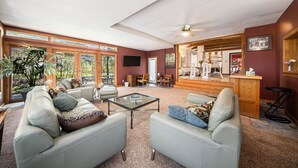 Ein geräumiges Wohnzimmer mit großem Fenster, Deckenventilator und einer Bar.