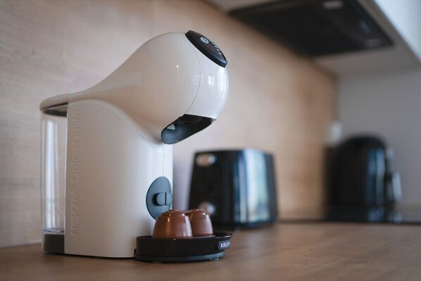 Una cafetera de diseño elegante, con un panel de control y un portacopas que contiene dos tazas.