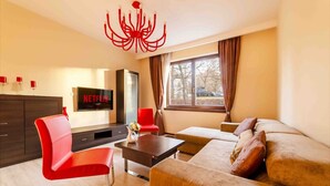 A modern living room with a sofa, red chairs, a coffee table, and a TV displaying 'NETFLIX'.
