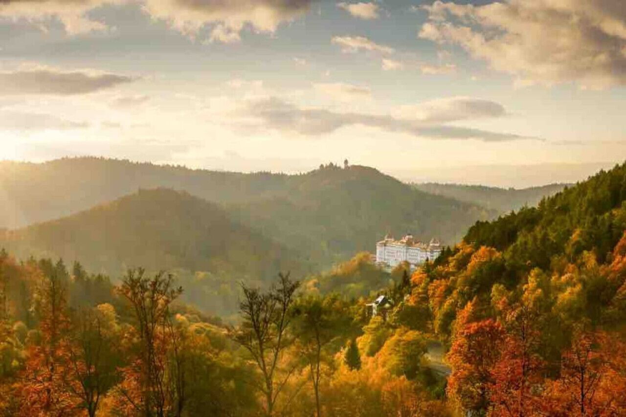 A hotel nestled in a mountainous area with autumn foliage.