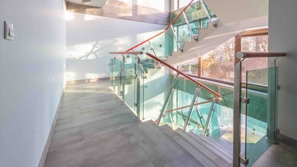 A modern interior with a glass staircase leading to an outdoor area.