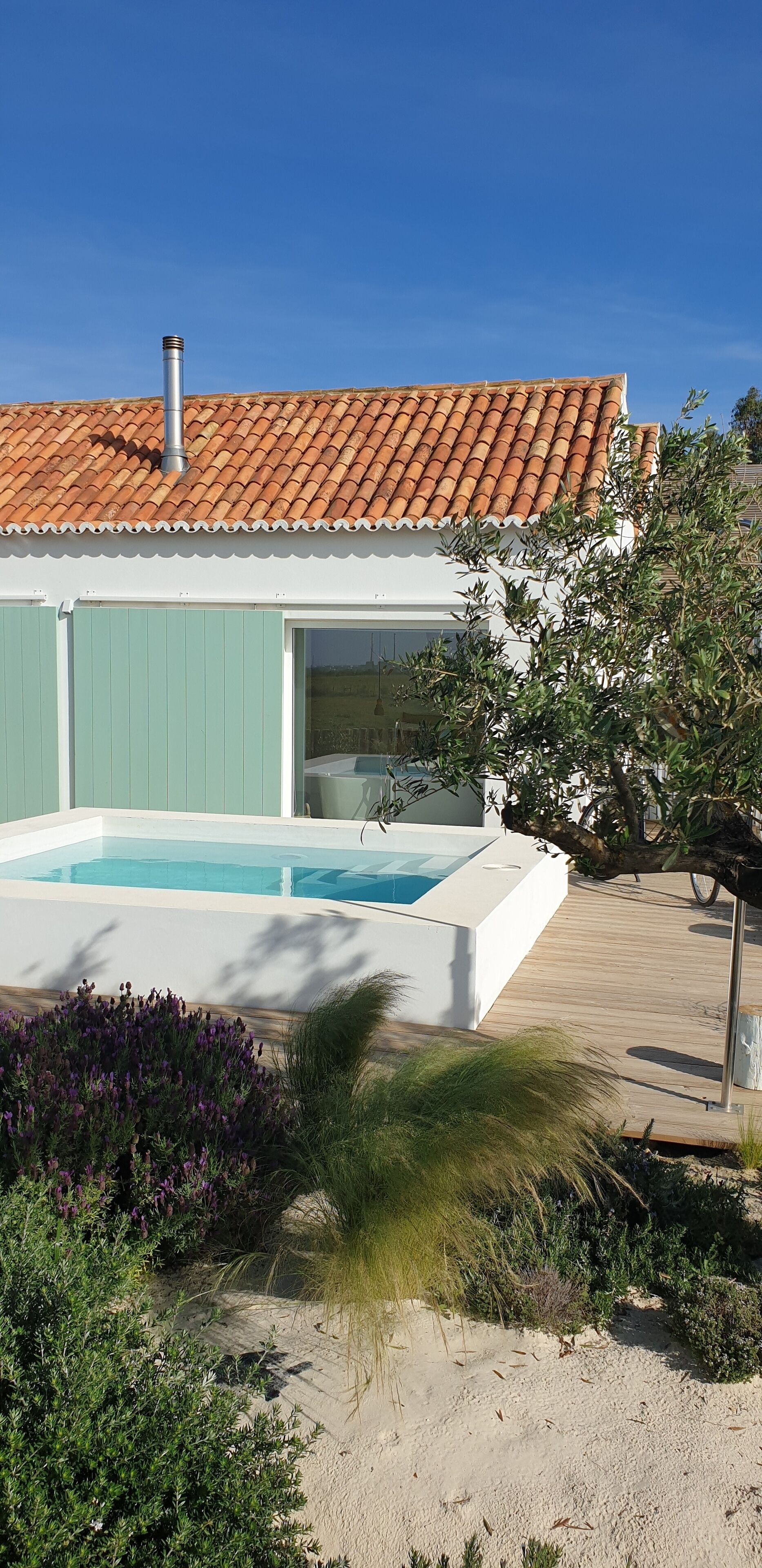 Ein modernes Haus mit Schwimmbad, grünen Fensterläden und einem Ziegeldach.