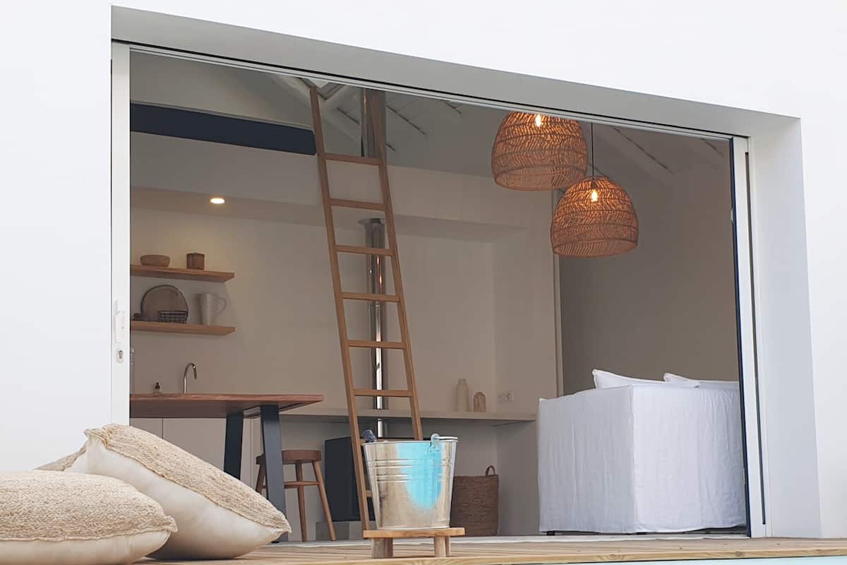 A modern interior with a pool, a wooden ladder, and a white bed.