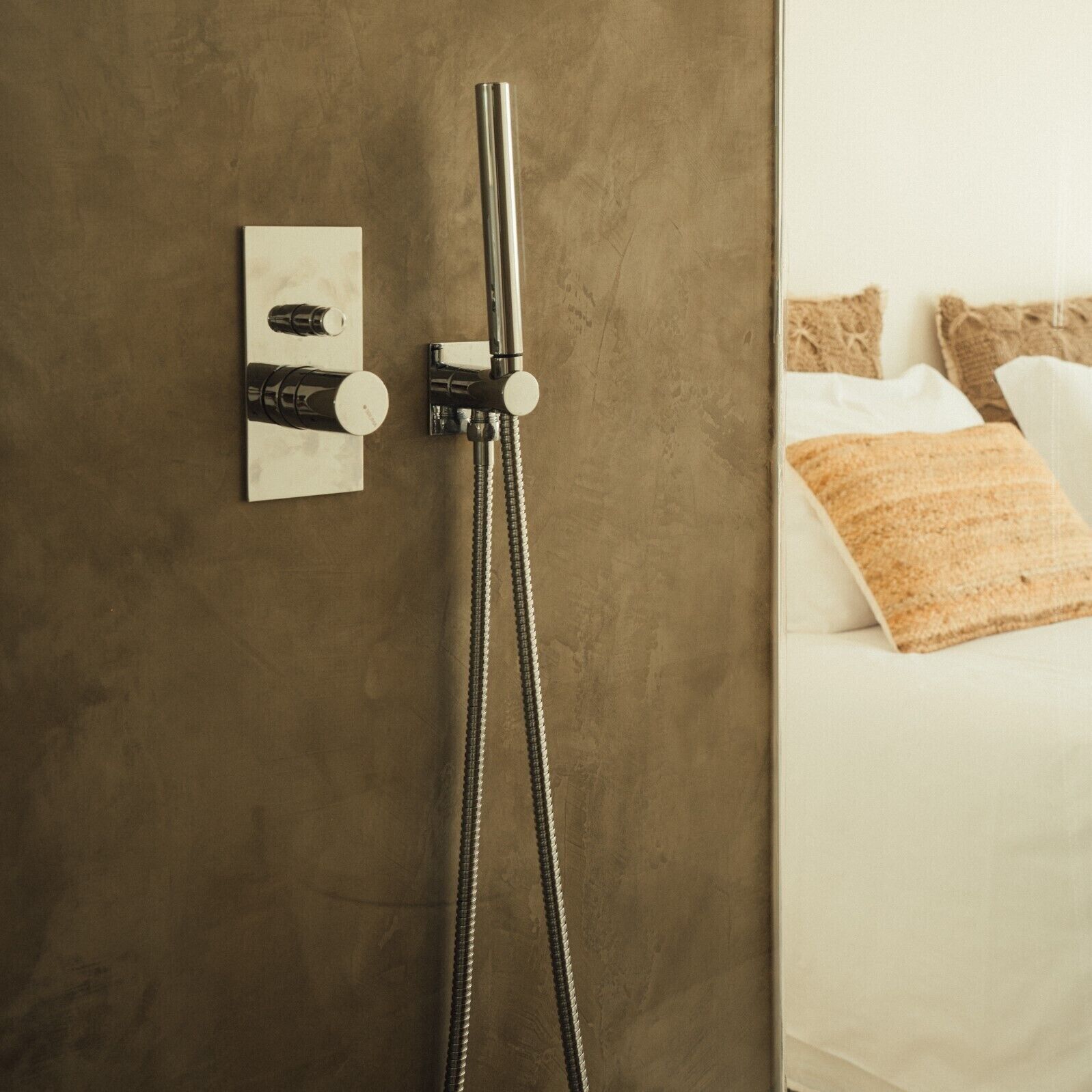 Une douche équipée d’un flexible, d’un panneau de commande et d’un porte-serviettes.
