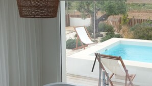 Ein modernes Badezimmer mit einer freistehenden Badewanne, einer Pendelleuchte aus Weidwerk und Blick auf einen Außenpool.