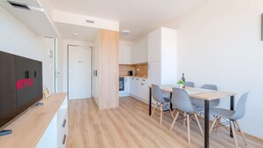 Une cuisine moderne avec des meubles blancs, un plan de travail en bois et un coin repas comprenant une table et des chaises.