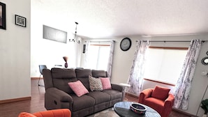 A modern living room with a sofa, two armchairs, a coffee table, and a patterned rug. - Cozy and Charming Amber Valley Haven in Fargo (Fargo)