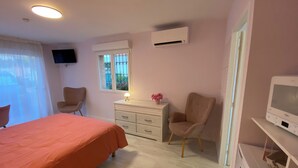 Een slaapkamer met een bed, een bureau, een stoel, een televisie en een airconditioner.
