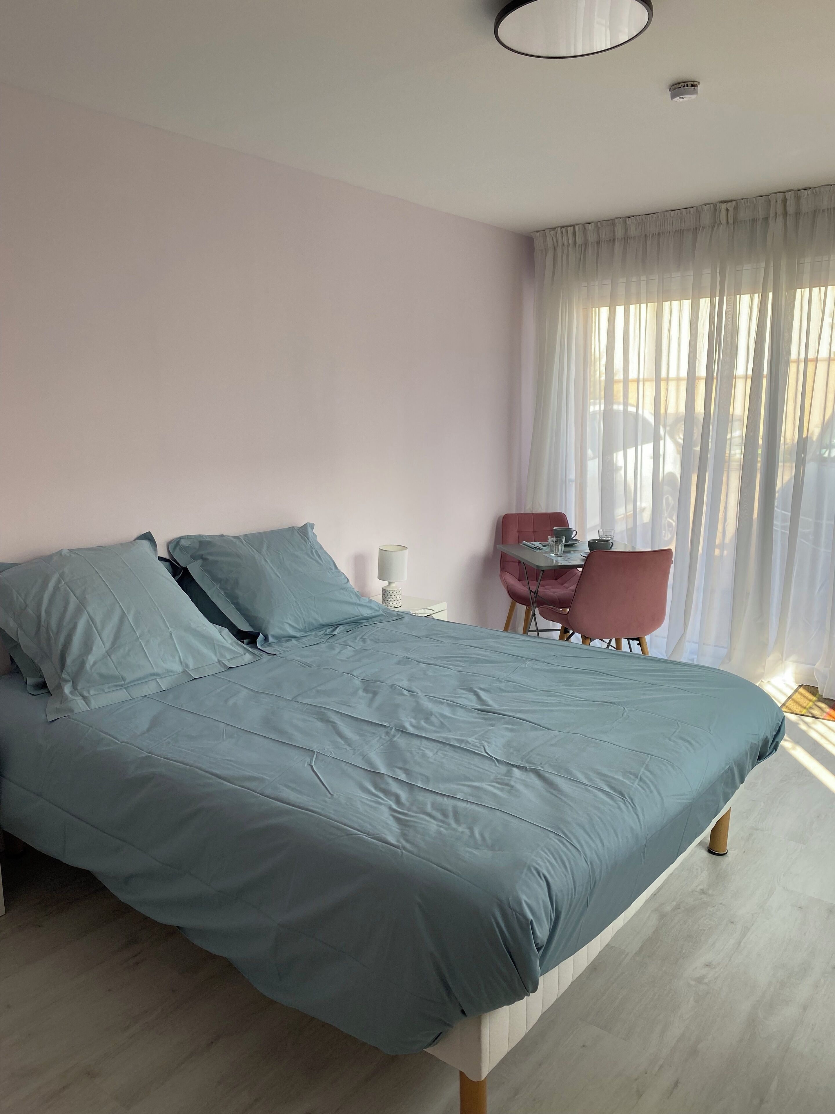 Un dormitorio con cama, una silla, una mesa y una ventana con cortinas.