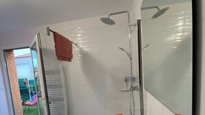 Een moderne badkamer met een wit wastafel, een grote spiegel en een douche.