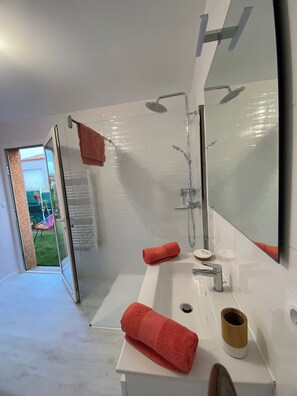 Een moderne badkamer met een wit wastafel, een grote spiegel en een douche.