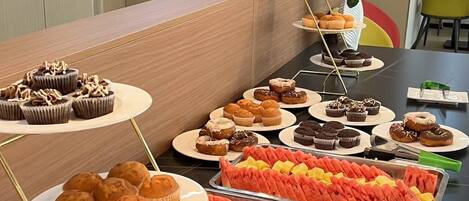 Una mesa de buffet con diversos pasteles y rebanadas de sandía.