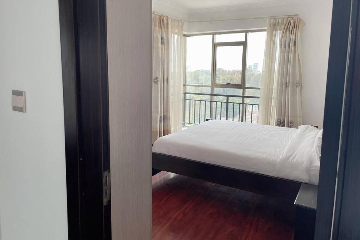 Una camera da letto con un letto, una finestra con tende, un balcone e una porta.