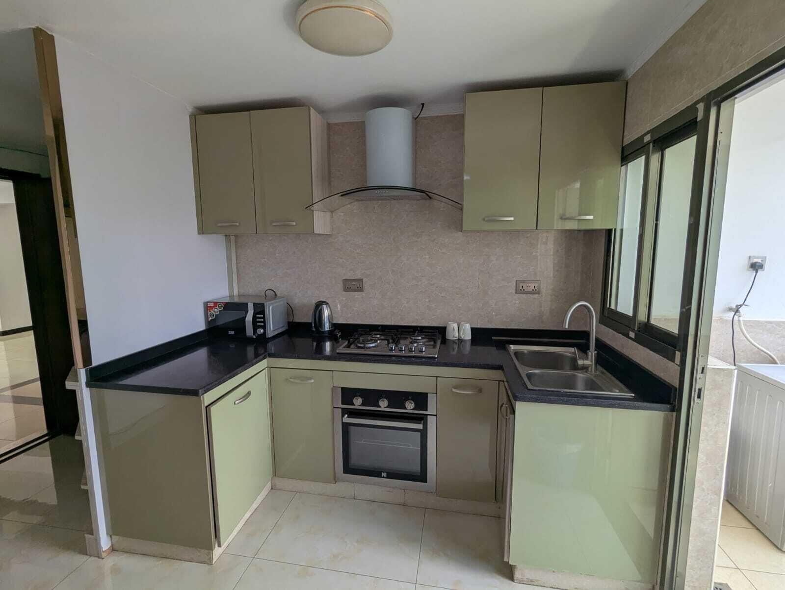 A compact kitchen with a gas stove, oven, and a kettle.